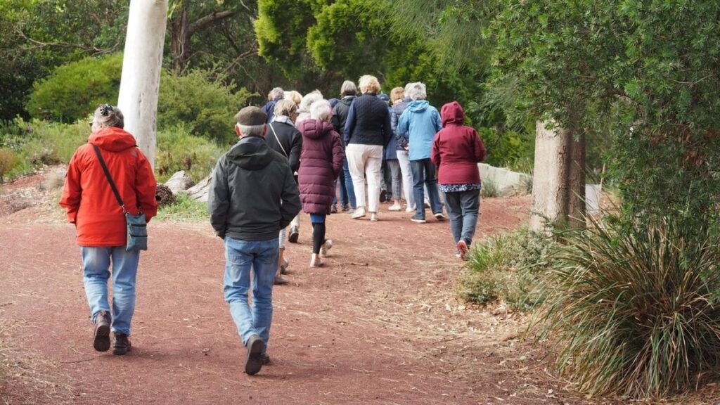 Visitors on a guided group tour walking along the trail through the native gardens at Kevin Hoffman Walk in Lara.